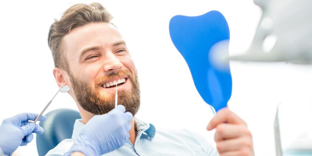 igienizare dentara, barbat care se uita in oglinda la dinti dupa o igienizare dentara | Trident